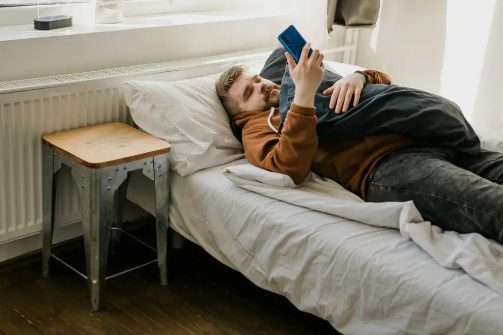 Freelance man using mobile phone checking social media network feed or message chat during lying on