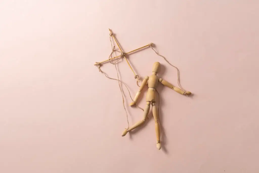 a wooden puppet marionette doll with threads isolated flat lay